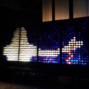 A Lite-Brite toy creating an image of a rocket taking off, with colorful pegs forming the rocket and its trail against a dark background.