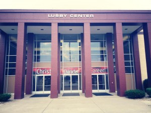 A building entrance with three large signs above the doors that read "Christ," "Character," and "Career." The structure features tall pillars and large windows.