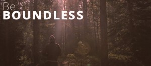 A person wearing a hoodie stands in a forest with sunlight streaming through the trees. The text overlay reads "Admissions: Be BOUNDLESS.