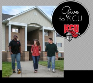 Three people walk together on a path in front of a two-story building with white columns. A circular graphic on the right features "to KCU" and a knight logo with "KCU" text.
