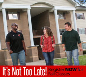 Three people walk in front of a building with columns. The person on the left is wearing a black shirt, the person in the middle is wearing a red plaid shirt, and the person on the right is wearing a green hoodie.