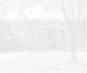 A white two-story building with large columns at the entrance, surrounded by trees. The scene is overexposed, making the details faint.