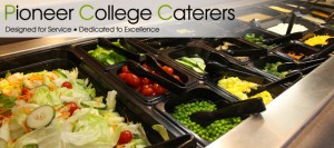 Salad bar with various fresh vegetables including lettuce, cucumbers, cherry tomatoes, peas, and sliced bell peppers, offered by Pioneer College Caterers. .