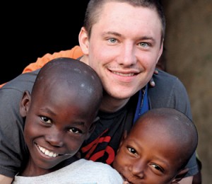 A man smiling with two children, who are also smiling.