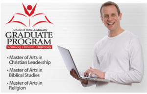 A man holding a laptop smiles near the Kentucky Christian University School of Bible & Ministry Graduate Program sign. Programs listed: Master of Arts in Christian Leadership and Biblical Studies.